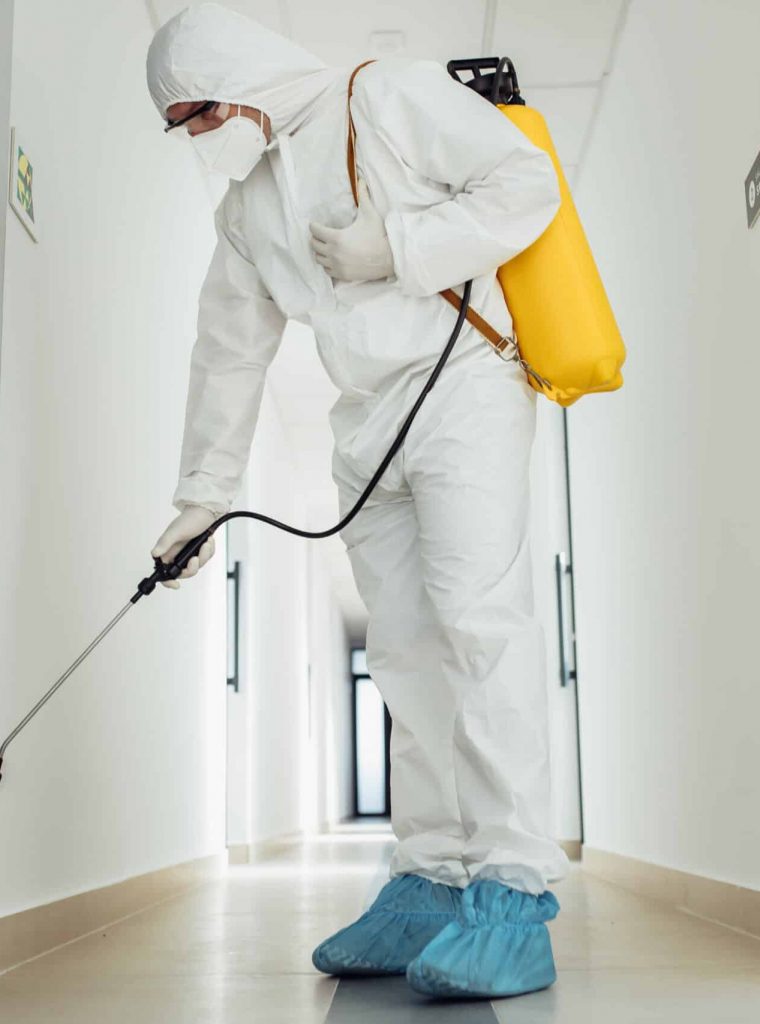 Office disinfection during COVID-19 pandemic. Man in protective suit and face mask spraying for disinfection in the office Office disinfection during COVID-19 pandemic. Man in protective suit and face mask spraying for disinfection in the office